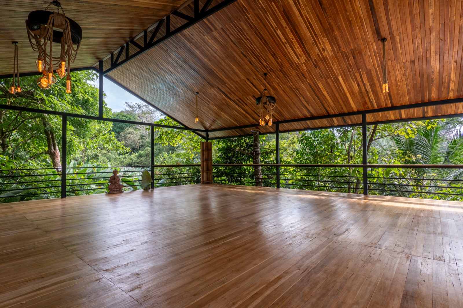 Open-air yoga deck with wooden ceiling in tropical jungle
