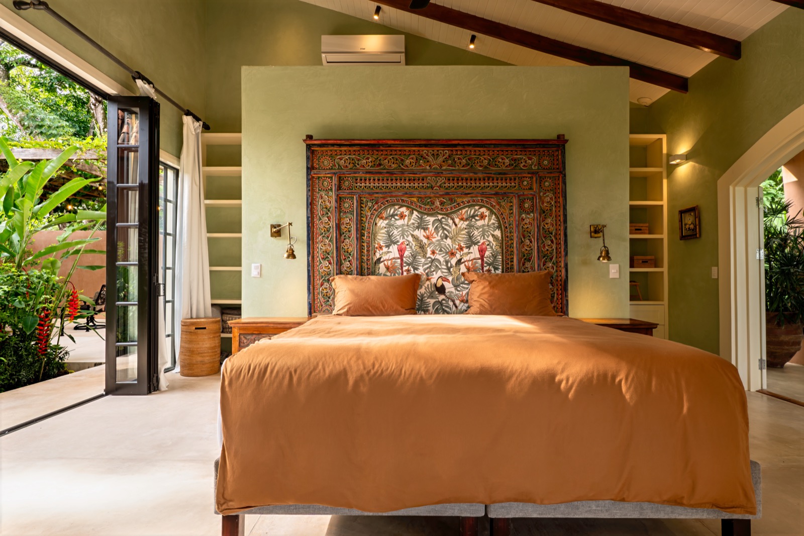Tropical bedroom with ornate headboard and green walls