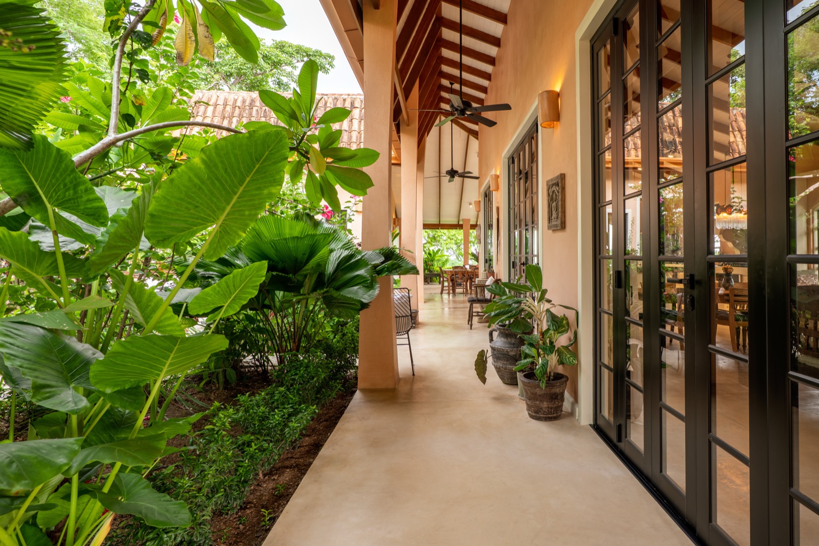Covered tropical walkway with potted plants and greenery